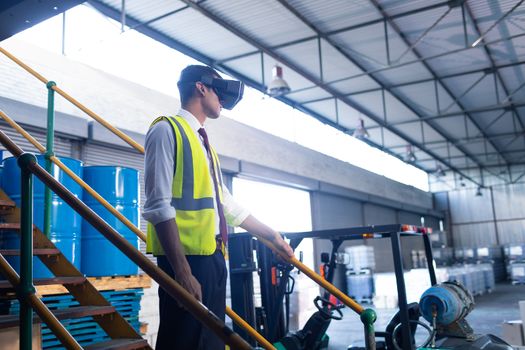 Side view of young Caucasian male supervisor using virtual reality headset in warehouse. This is a freight transportation and distribution warehouse. Industrial and industrial workers concept