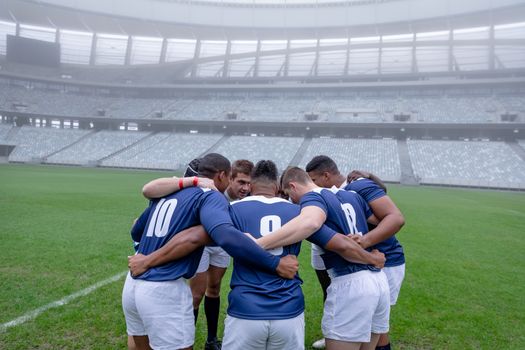 Side view of group of male rugby players forming huddles in the morning at stadium