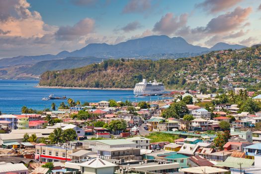 A huge white luxury cruise ship anchored in the bay on a tropical island