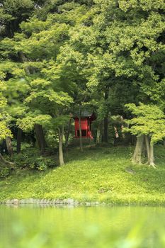 Small Shrine Vermilion Red Shinto located on the Osensui Lake islet of Koishikawa Korakuen Park in Bunkyo Ward, Tokyo. This small, heavily forested island is an evocation of the mythical Mount Horai very important in Chinese mythology.