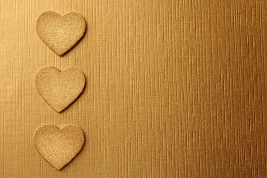 The picture shows golden hearts on a golden background