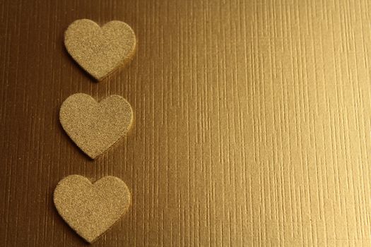 The picture shows golden hearts on a golden background