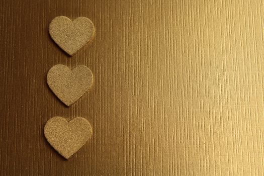 The picture shows golden hearts on a golden background