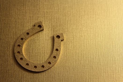 The picture shows a golden horseshoe on a golden background