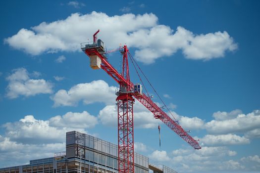 A new construction tower topped with a red crance under a blue sky