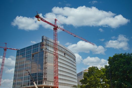 Two red cranes rising over a new construction project