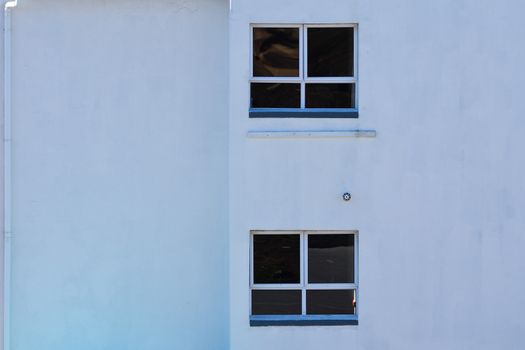 Plain white plaster wall with two windows building feature close-up, Mossel Bay, South Africa