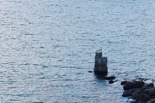 A rocky outcrop with weathered landmark beacon extending into the bay, Cape Town, South Africa