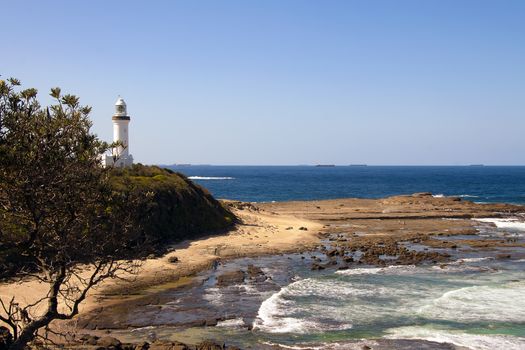 High angle shot of a lighthouse on a headland above a rocky beach platform and sea