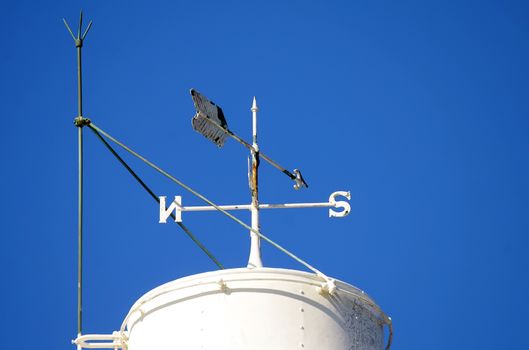 close up shot of windvane showing north and south against the blue sky