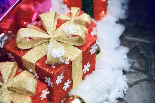 A red gift box with a golden bow on a white cotton floor For decorating the New Year's venue There is space to put text. Selective focus.