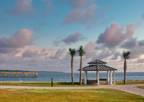 A pavilion and palm trees on the coast by a pier