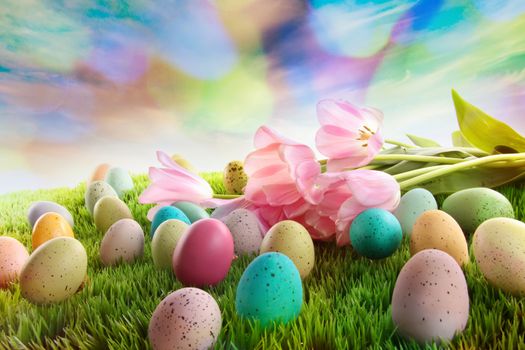 Easter eggs with tulips on grass with rainbow sky
