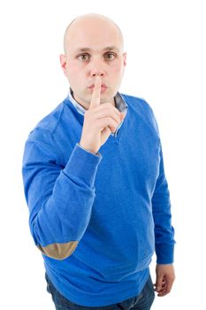 portrait of a young bald man making a shushing gesture with his finger, isolated on a white studio background.