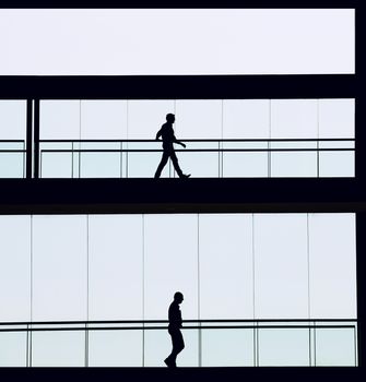Silhouette view of two businessmen in a modern office building interior with panoramic windows.