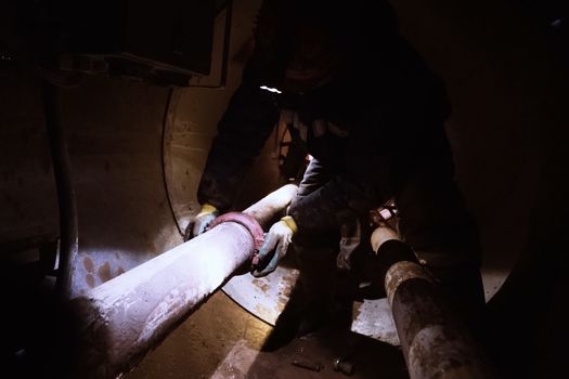 The worker in the tunnel is repairing the pipeline. Repair work.