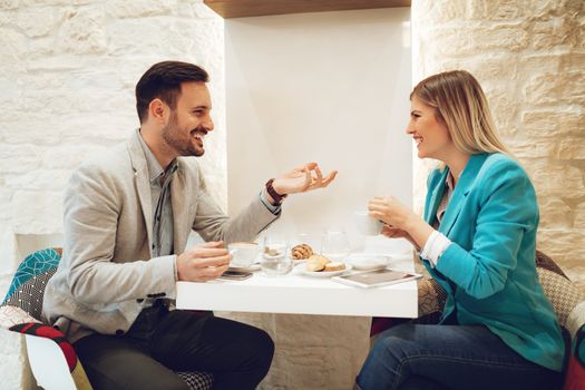 Smiling young man and young woman talking and drinking coffee in a cafe. 