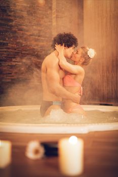 Beautiful young couple enjoying in a hot tub at the spa centre.