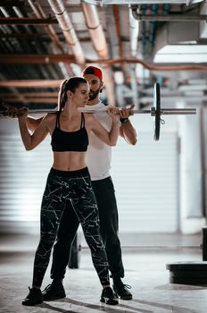 Young muscular woman doing cross workout with a personal trainer at the garage gym.