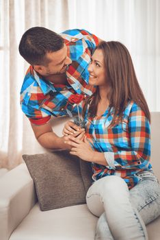 Handsome young man in love give red rose to his girlfriend in an apartment.