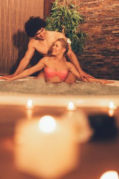 Beautiful young couple enjoying in a hot tub at the spa centre.