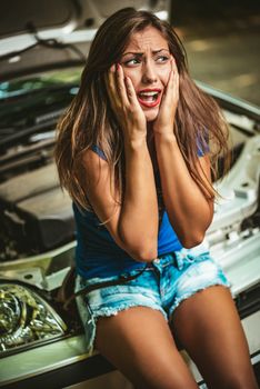 Beautiful young woman screaming with despair when realizing that her car broke down. 