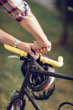 Close-up of a unrecognizable man repairing bicycle handlebar on a street.