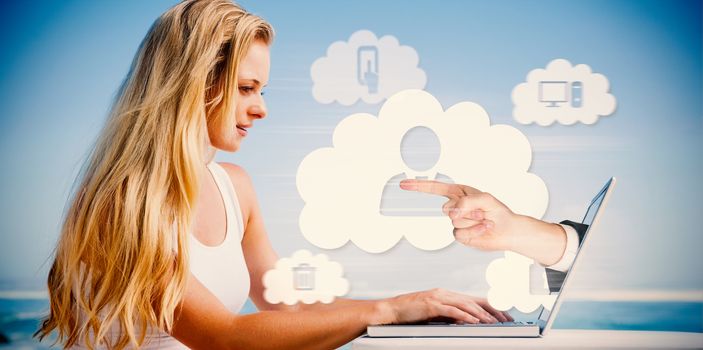 Composite image of pretty blonde using her laptop at the beach with hand presenting