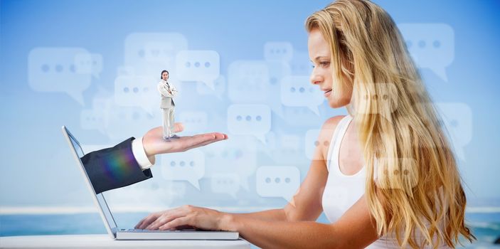 Composite image of pretty blonde using her laptop at the beach with hand presenting businessman