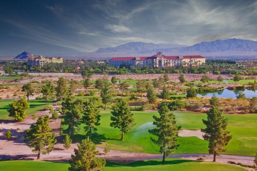 A resort in the desert between a golf course and mountains