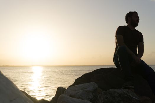 Man sitting on the rocks enjoying the sunset