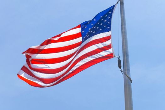 American flag on a pole. The flag flies by the wind.