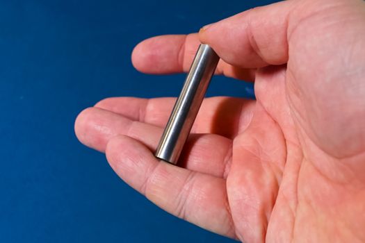 Tungsten rod in the hand. A piece of tungsten for experiments.