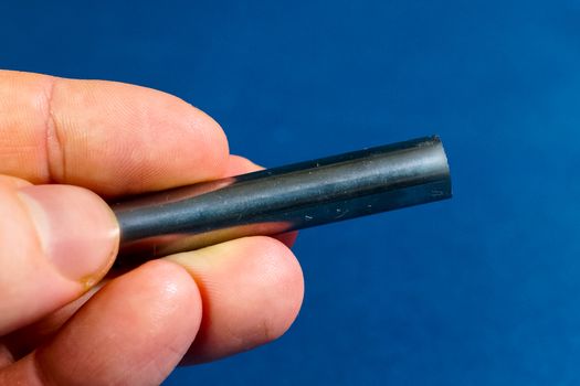 Tungsten rod in the hand. A piece of tungsten for experiments.