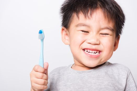 Closeup Asian face, Little children boy hand holds toothbrush he brushing teeth myself on white background with copy space, health medical care