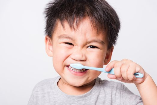 Closeup Asian face, Little children boy hand holds toothbrush he brushing teeth myself on white background with copy space, health medical care