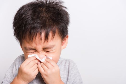 Closeup Asian face, Little children boy cleaning nose with tissue on white background with copy space, health medical care