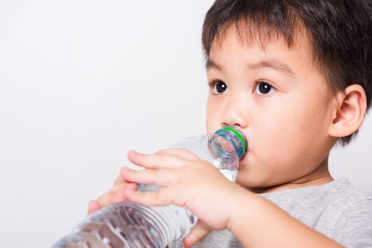 Closeup Asian face, Little children boy drinking water from Plastic bottle on white background with copy space, health medical care