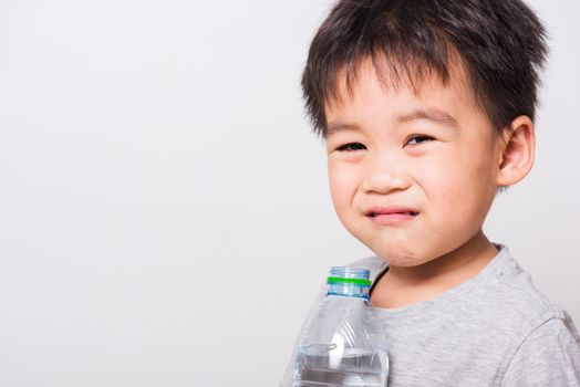 Closeup Asian face, Little children boy drinking water from Plastic bottle on white background with copy space, health medical care