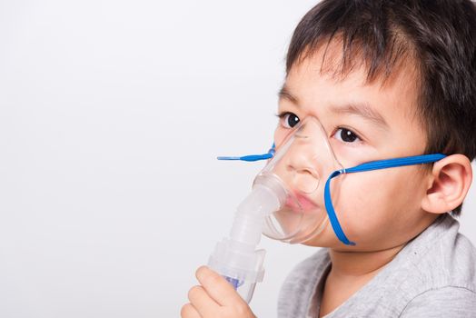 Closeup Asian face, Little children boy sick he using steam inhaler nebulizer mask inhalation oneself on white background, health medical care