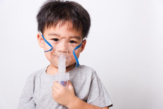 Closeup Asian face, Little children boy sick he using steam inhaler nebulizer mask inhalation oneself on white background, health medical care