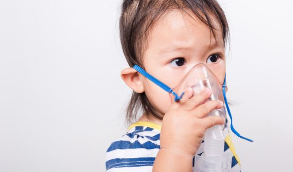 Closeup Asian face, Little baby girl sick her using steam inhaler nebulizer mask inhalation oneself on white background with copy space, health medical care