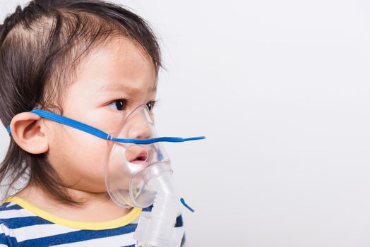 Closeup Asian face, Little baby girl sick her using steam inhaler nebulizer mask inhalation oneself on white background with copy space, health medical care