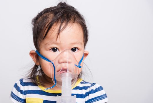 Closeup Asian face, Little baby girl sick her using steam inhaler nebulizer mask inhalation oneself on white background with copy space, health medical care