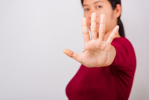 Asian beautiful woman itching her outstretched hand showing stop gesture front face, focus on hand on white background with copy space