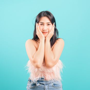 Smiling face Asian beautiful woman her touching face skin care on blue background, with copy space for text