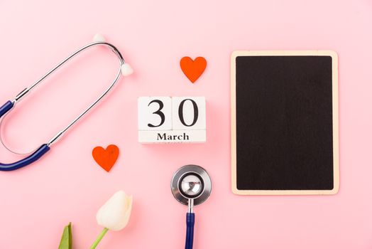 Doctor's Day concept, flat lay top view, equipment medical red heart stethoscope on pink background, care patient in hospital with black board copy space for text