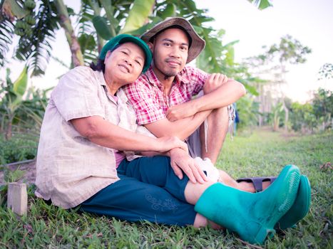 Asian agriculturist, mother and son, sitting on yard in their garden, Thailand