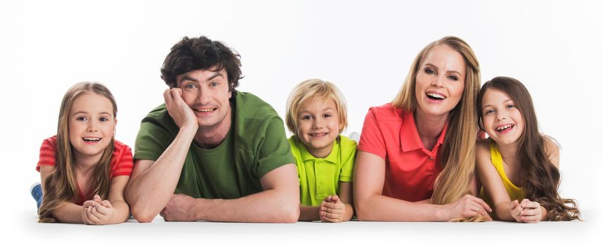 Happy family of parents and three children laying on floor isolated on white background