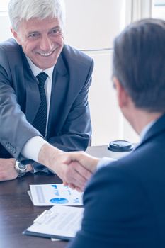 Business people shaking hands at meeting table happy smiling successful negotiation concept